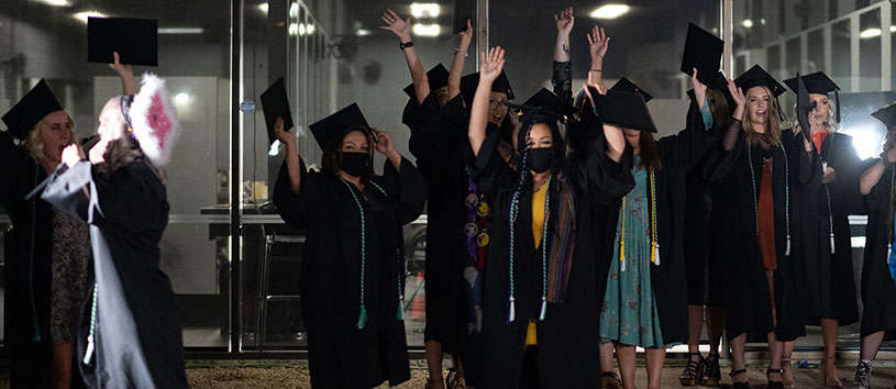 Penrose graduates throwing their caps in the air at their graduation event.